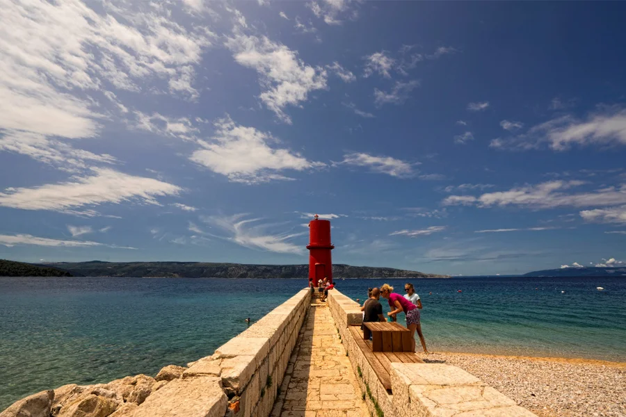 Pebble beach and red lighthouse on Cres Island