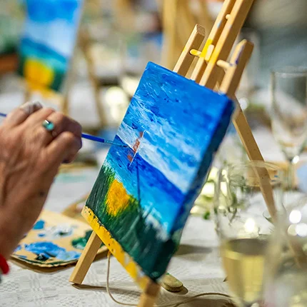 Teilnehmerin malt auf Leinwand beim Paint & Wine Workshop im Camp Kovačine
