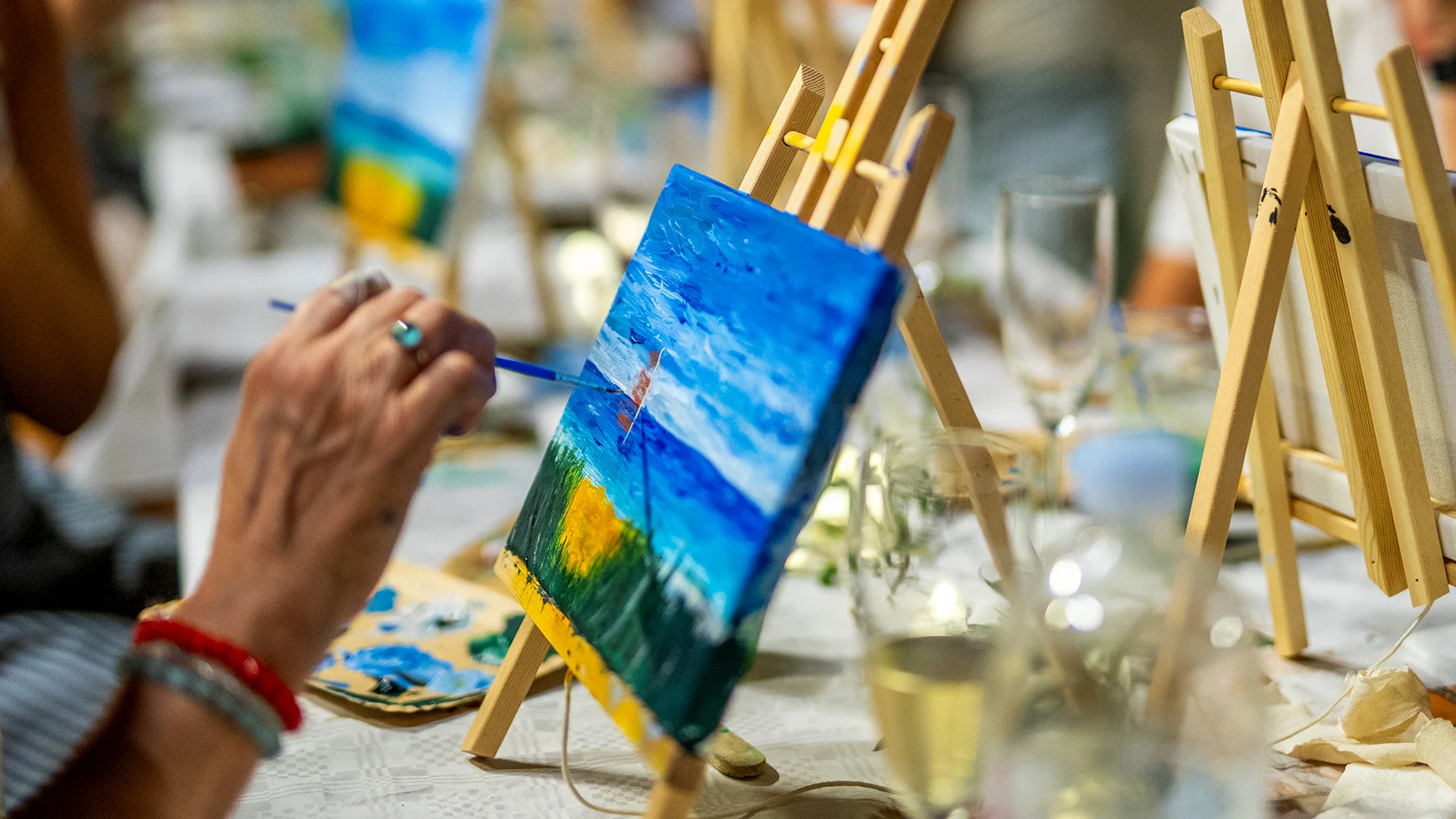Teilnehmerin malt auf Leinwand beim Paint & Wine Workshop im Camp Kovačine